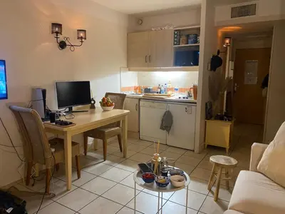 a living room with a table and a kitchen at Studio 50M de la mer in Saint-Laurent-du-Var