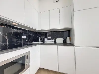 a white kitchen with black and white appliances at Nestor&Jeeves - EMERAUDE - Central - Modern in Nice