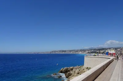 a walkway next to the ocean with people walking on it at 