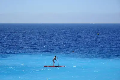 a person standing on a paddle board in the ocean at 