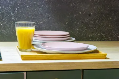a glass of orange juice sitting on a table with plates at Charmant studio refait à neuf quartier du port in Nice