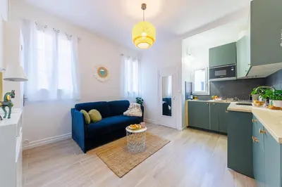 a living room with a blue couch and a kitchen at Charmant studio refait à neuf quartier du port in Nice