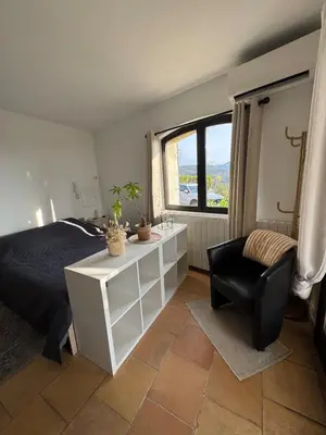 a bedroom with a bed and a chair and a window at Maison Lou in Falicon