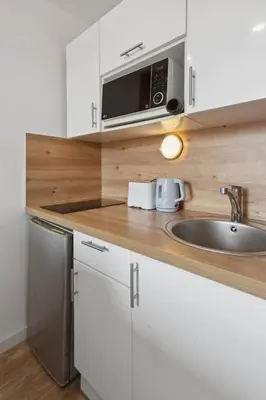 a kitchen with white cabinets and a sink and a microwave at L'Opéra - Hypercentre - Cosy - No elevator - Minimalist - Sea in Nice