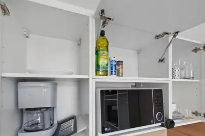 a kitchen with white shelves and a microwave oven at L'Opéra - Hypercentre - Cosy - No elevator - Minimalist - Sea in Nice