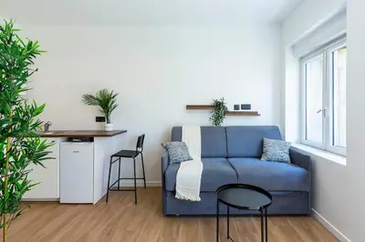 a living room with a blue couch and a table at Villa Maska - Studios avec Terrasse proche plage et aéroport de Nice in Nice