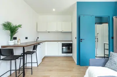 a kitchen with a table and a blue refrigerator at Villa Maska - Studios avec Terrasse proche plage et aéroport de Nice in Nice