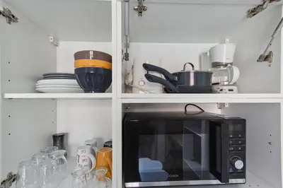 a kitchen with a microwave and some dishes on shelves at Le Citadin - Hypercentre - Cosy - Shopping - WIFI in Nice