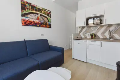 a living room with a blue couch and a kitchen at Le Citadin - Hypercentre - Cosy - Shopping - WIFI in Nice