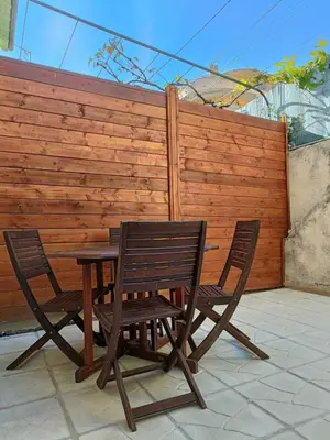 a wooden table and two chairs next to a fence at Appartement studio in Nice