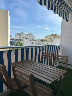 a wooden bench and two chairs on a balcony at Riviera Retreat - Steps to Beach & Shops, Balcony & AC in Saint-Laurent-du-Var