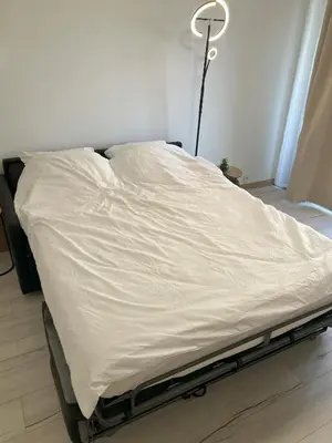 a bed with a white sheet on it in a room at Riviera Retreat - Steps to Beach & Shops, Balcony & AC in Saint-Laurent-du-Var