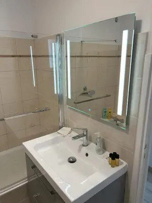 a bathroom with a sink and a mirror and a tub at Riviera Retreat - Steps to Beach & Shops, Balcony & AC in Saint-Laurent-du-Var