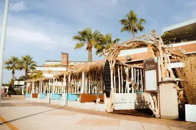 a building with palm trees on the side of a street at Riviera Retreat - Steps to Beach & Shops, Balcony & AC in Saint-Laurent-du-Var