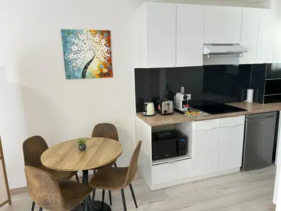 a kitchen with a table and chairs in a kitchen at Riviera Retreat - Steps to Beach & Shops, Balcony & AC in Saint-Laurent-du-Var