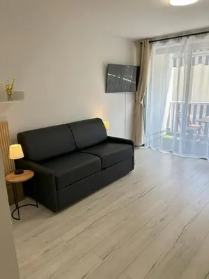 a black couch in a living room with a window at Riviera Retreat - Steps to Beach & Shops, Balcony & AC in Saint-Laurent-du-Var