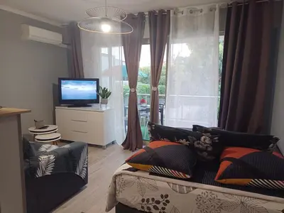 a living room with a couch and a tv and a window at Studio calme proximité plage in Saint-Laurent-du-Var