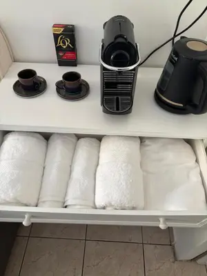 a coffee maker and cups on a shelf with towels at Cœur de Nice - Plage à 5min in Nice