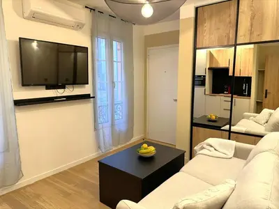 a living room with a couch and a tv on a wall at Studio Californien à deux pas de la plage in Nice