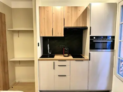 a kitchen with white appliances and wooden cabinets at Studio Californien à deux pas de la plage in Nice