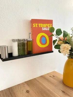 a shelf with a book and a vase on a table at Le Spot Niçois in Nice