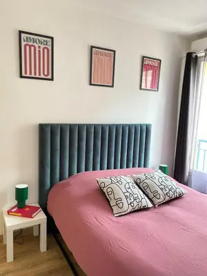 a bedroom with a pink bed with a black headboard at Le Spot Niçois in Nice