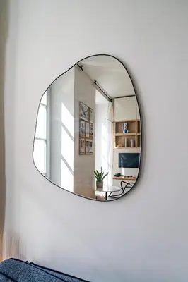 a round mirror on a white wall in a living room at Studio lumineux Centre-ville in Nice