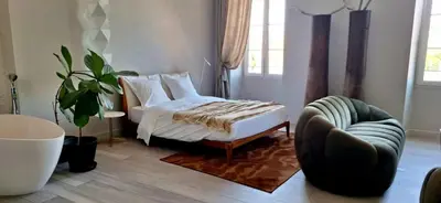 a bedroom with a bed and a chair at Les Suites Massena in Nice