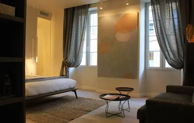 a bedroom with a bed and a couch and windows at Les Suites Massena in Nice