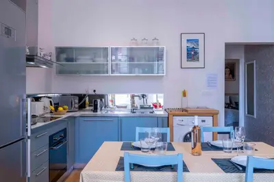 a kitchen with blue cabinets and a table and chairs at Beautiful Provencal apartment, fully equipped, beach 300m away - FONTAINE 3 in Nice
