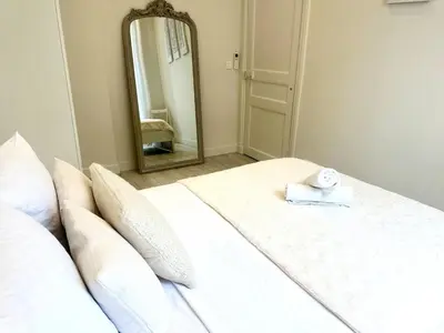 a bedroom with a white bed with a mirror at Harmonie Nature au cœur de Nice in Nice