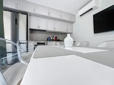 a kitchen with white cabinets and a table and chairs at Azur Stay in Nice