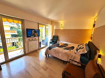 a bedroom with a bed and a television and a balcony at STUDIO BALCON CALME AVEC PARKING 5mn de la MER in Nice