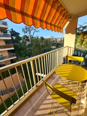 a yellow chair and an umbrella on a balcony at STUDIO BALCON CALME AVEC PARKING 5mn de la MER in Nice