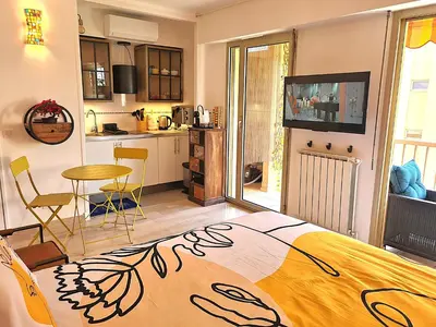 a bedroom with a bed and a table and a kitchen at STUDIO BALCON CALME AVEC PARKING 5mn de la MER in Nice
