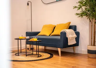 a blue couch with yellow pillows and two tables at Duplex Saveria - Terrace - Netflix - Beach in Nice