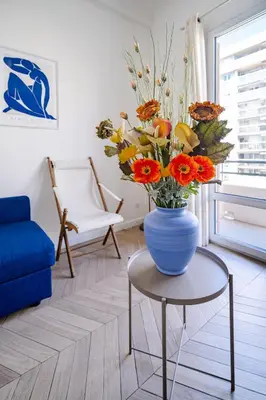 a blue vase with flowers on a table in a living room at Studio moderne proche mer - Balcon et Climatisé in Nice