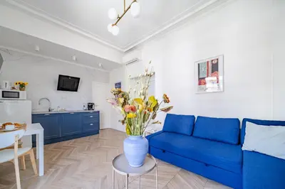 a living room with a blue couch and a vase of flowers at Studio moderne proche mer - Balcon et Climatisé in Nice