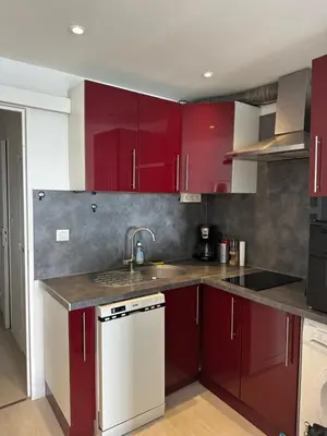 a kitchen with red cabinets and a sink at Appartement vue mer CALIFORNIE PROMENADE DES ANGLAIS in Nice
