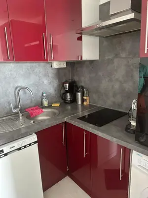 a kitchen with red cabinets and a sink at Appartement vue mer CALIFORNIE PROMENADE DES ANGLAIS in Nice