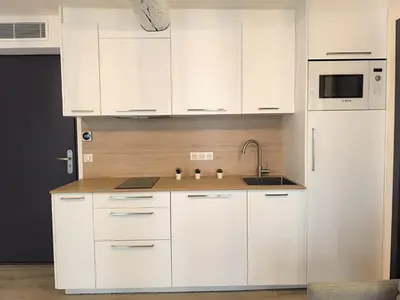 a white kitchen with white cabinets and a sink at Seytour Central Place in Nice