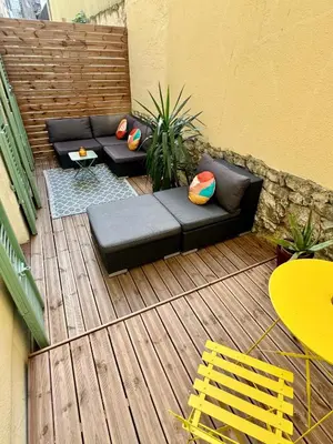 a patio with a couch and chairs on a wooden deck at Joli 2 pièces avec terrasse en centre ville in Nice