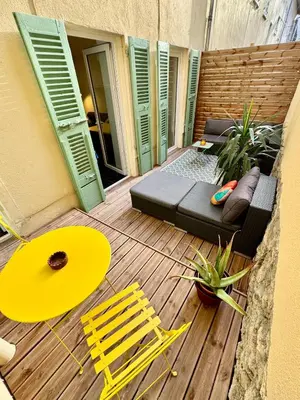 a patio with a couch and chairs on a wooden deck at Joli 2 pièces avec terrasse en centre ville in Nice
