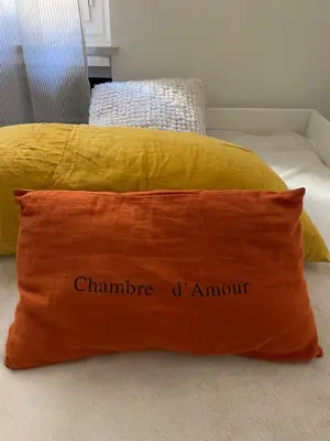 an orange pillow on a bed with a yellow pillow at Palais Libération 3 pièces in Nice