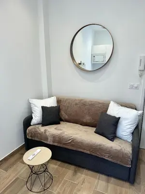 a living room with a couch and a mirror at Cosy studio le port in Nice