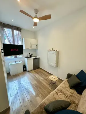 a living room with a couch and a kitchen at Cosy studio le port in Nice