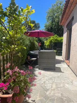 a patio with a table and a purple umbrella at La Petite Maison des Baous in Saint-Jeannet