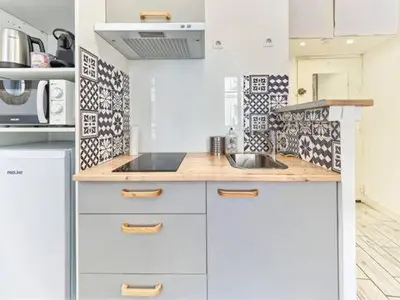 a kitchen with white cabinets and black and white tiles at Studio Hyper Centre - WIFI - Central in Nice
