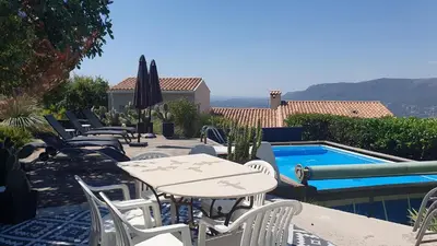 a patio with tables and chairs next to a swimming pool at APPART DANS VILLA AVEC GRANDE TERRASSE PRIVATIVe in Aspremont