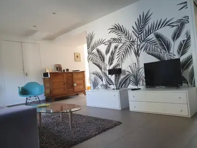 a living room with a tv and a palm tree mural at APPART DANS VILLA AVEC GRANDE TERRASSE PRIVATIVe in Aspremont
